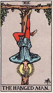 The Rider-Waite-Smith Hanged Man tarot card depicting a serene figure suspended upside down from a wooden cross by one foot.