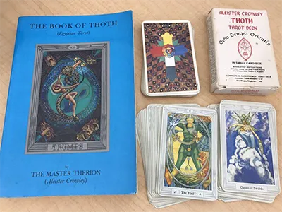 A detailed view of multiple Thoth Tarot cards displaying geometric lines and dense occult insignia.